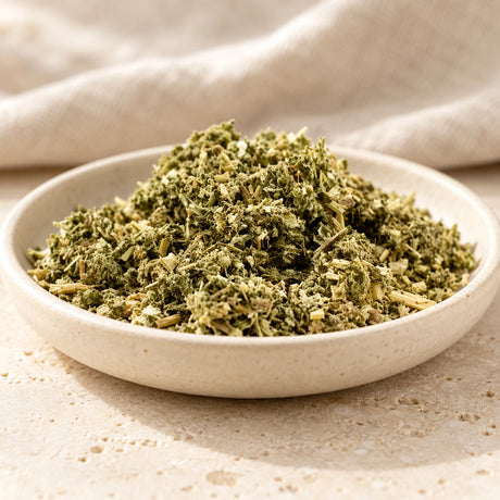 Dried mugwort herb in an ivory dish on pale stone